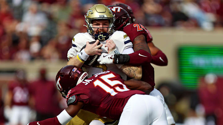 Oct 26, 2024; Blacksburg, Virginia, USA; Georgia Tech Yellow Jackets quarterback Zach Pyron (5) is tackled by Virginia Tech Hokies safety Jaylen Jones (15) and linebacker Jaden Keller (24) during the first quarter at Lane Stadium. Mandatory Credit: Peter Casey-Imagn Images
