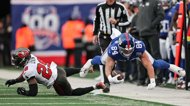 Nov 24, 2024; East Rutherford, New Jersey, USA; New York Giants tight end Theo Johnson (84) is tackled by Tampa Bay Buccaneers safety Christian Izien (29) during the second half at MetLife Stadium.  