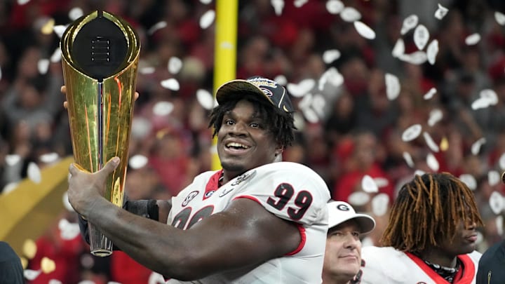 Jan 10, 2022; Indianapolis, IN, USA; Georgia Bulldogs defensive lineman Jordan Davis (99) hold the National Championship trophy after defeating the Alabama Crimson Tide in the 2022 CFP college football national championship game at Lucas Oil Stadium. Mandatory Credit: Kirby Lee-Imagn Images