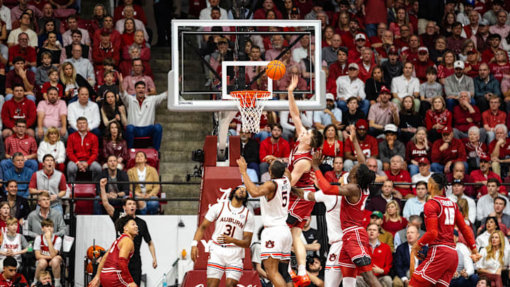 Feb 15, 2025; Tuscaloosa, Alabama, USA; Alabama Crimson Tide forward Grant Nelson (4) shoots against Auburn Tigers forward Chris Moore (5) and forward Chaney Johnson (31) during the first half at Coleman Coliseum. Mandatory Credit: Will McLelland-Imagn Images
