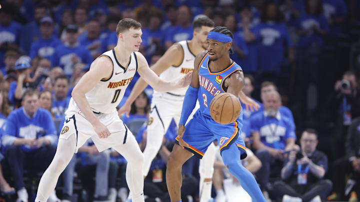 May 18, 2025; Oklahoma City, Oklahoma, USA; Oklahoma City Thunder guard Shai Gilgeous-Alexander (2) passes around Denver Nuggets guard Christian Braun (0) in the second quarter during game seven of the second round for the 2025 NBA Playoffs at Paycom Center. Mandatory Credit: Alonzo Adams-Imagn Images