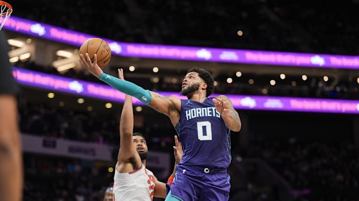 Mar 20, 2025; Charlotte, North Carolina, USA; Charlotte Hornets forward Miles Bridges (0) drives to the basket against New York Knicks center Karl-Anthony Towns (32) during the second half at Spectrum Center. Mandatory Credit: Jim Dedmon-Imagn Images