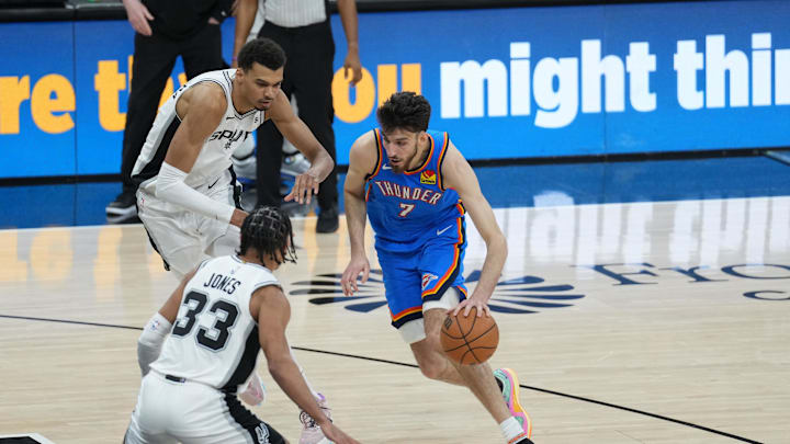 Feb 29, 2024; San Antonio, Texas, USA;  Oklahoma City Thunder forward Chet Holmgren (7) dribbles against San Antonio Spurs guard Tre Jones (33) and center Victor Wembanyama (1) in the second half at Frost Bank Center. Mandatory Credit: Daniel Dunn-Imagn Images