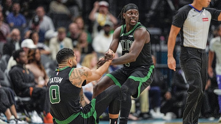 Boston Celtics guard Jrue Holiday (4) helps forward Jayson Tatum (0) onto his feet after a foul late during the second half against the Charlotte Hornets at the Spectrum Center.