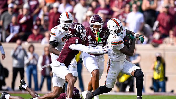 Dec 20, 2025; College Station, TX, USA; Miami Hurricanes running back Mark Fletcher Jr. (4) eludes the tackle of Texas A&M Aggies cornerback Dezz Ricks (2) and cornerback Jordan Shaw (8) during the game between the Aggies and the Hurricanes at Kyle Field. Mandatory Credit: Jerome Miron-Imagn Images Dec 20, 2025; College Station, TX, USA; Miami Hurricanes running back Mark Fletcher Jr. (4) eludes the tackle of Texas A&M Aggies cornerback Dezz Ricks (2) and cornerback Jordan Shaw (8) during the game between the Aggies and the Hurricanes at Kyle Field. Mandatory Credit: Jerome Miron-Imagn Images