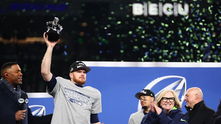 Jan 25, 2026; Seattle, WA, USA; Seattle Seahawks quarterback Sam Darnold (14) celebrates with the trophy on the podium after defeating the Los Angeles Rams in the 2026 NFC Championship Game at Lumen Field. Mandatory Credit: Kevin Ng-Imagn Images