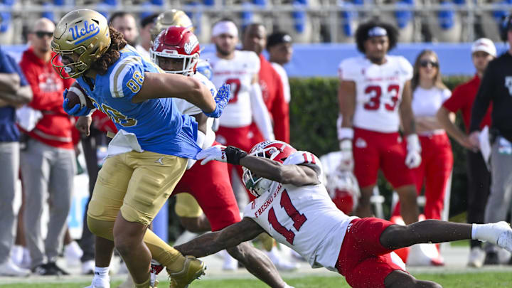 Nov 30, 2024; Pasadena, California, USA; UCLA Bruins tight end Moliki Matavao (88) breaks a tackle by Fresno State Bulldogs defensive back Jayden Davis (11) during the first quarter at Rose Bowl. Mandatory Credit: Robert Hanashiro-Imagn Images