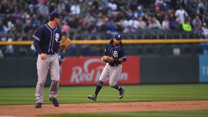 Aug 21, 2018; Denver, CO, USA; San Diego Padres shortstop Freddy Galvis (13) backs up right fielder Wil Myers (4) (left) following his fielding error delivers a pitch in the first inning against the Colorado Rockies at Coors Field. Mandatory Credit: Ron Chenoy-Imagn Images
