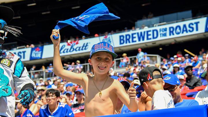 Aug. 15, 2026; Orchard Park, New York, USA; A young Buffalo Bills fan waves his shirt during a preseason game between the Bills and the Carolina Panthers at the new Highmark Stadium. 
