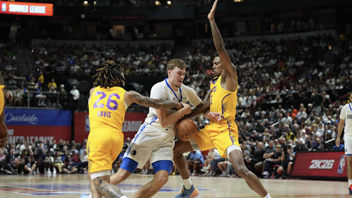 Jul 10, 2025; Las Vegas, NV, USA; Dallas Mavericks forward Cooper Flagg (32) dribbles against Los Angeles Lakers guard RJ Davis (26) and guard DaJaun Gordon (45) in the first quarter of their game at Thomas & Mack Center. Mandatory Credit: Candice Ward-Imagn Images