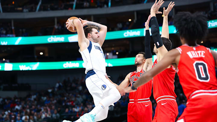 Dallas Mavericks guard Luka Doncic (77) passes over Chicago Bulls guard Zach LaVine (8) and Chicago Bulls center Nikola Vucevic (9) and Chicago Bulls guard Coby White (0) during the first quarter at American Airlines Center. Mandatory Credit: Kevin Jairaj-Imagn Images