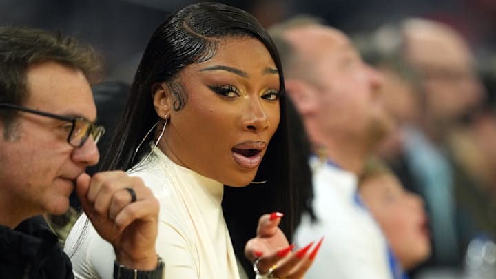 Dec 25, 2025; San Francisco, California, USA; Recording artist Megan Thee Stallion (center left) sits courtside during the first quarter of the game between the Golden State Warriors and the Dallas Mavericks at Chase Center.
