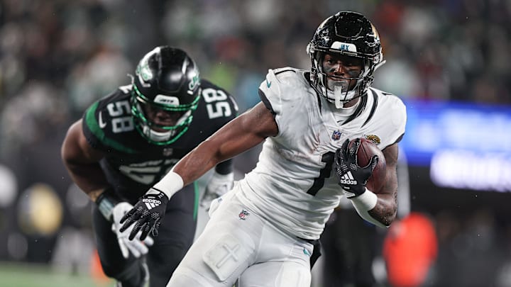 Dec 22, 2022; East Rutherford, New Jersey, USA; Jacksonville Jaguars running back Travis Etienne Jr. (1) carries the ball as New York Jets defensive end Carl Lawson (58) pursues during the first half at MetLife Stadium. Mandatory Credit: Vincent Carchietta-Imagn Images