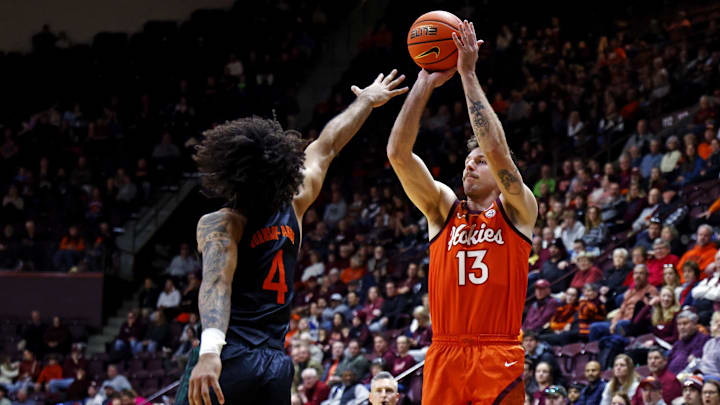 Jan 4, 2025; Blacksburg, Virginia, USA; Virginia Tech Hokies forward Ben Burnham (13) shoots the ball against Miami Hurricanes forward Isaiah Johnson-Arigu (4) during the first half at Cassell Coliseum. Mandatory Credit: Peter Casey-Imagn Images