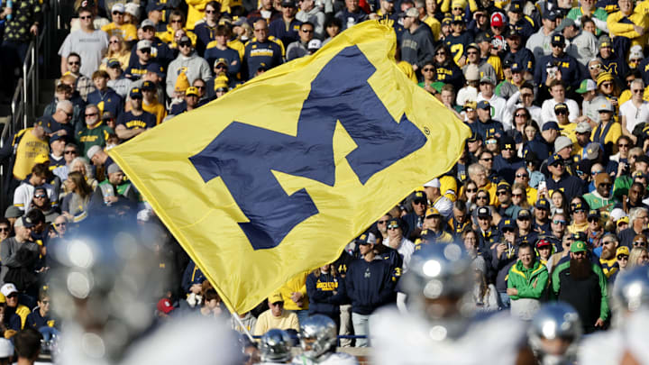 Nov 2, 2024; Ann Arbor, Michigan, USA;  Michigan Wolverines cheerleader runs with a flag before the game against the Oregon Ducks at Michigan Stadium. Mandatory Credit: Rick Osentoski-Imagn Images