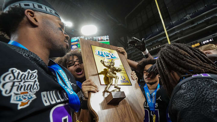 Brownsburg Bulldogs celebrate with the trophy Saturday, Nov. 29, 2025, during the IHSAA Class 6A state championship game at Lucas Oil Stadium in Indianapolis.