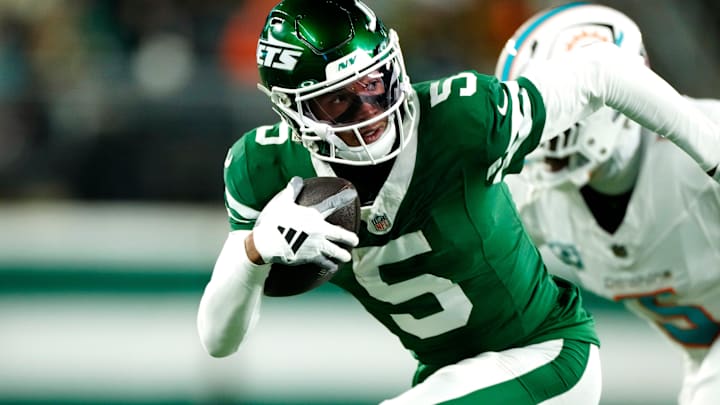 New York Jets wide receiver Garrett Wilson (5) runs with the ball past Miami Dolphins cornerback Jalen Ramsey (5), Sunday January 5, 2025, in East Rutherford.