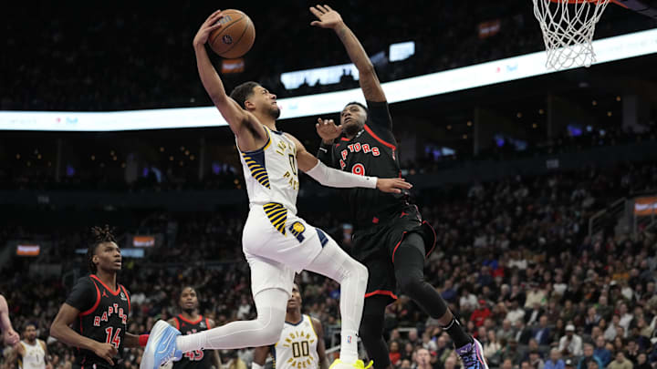 Dec 3, 2024; Toronto, Ontario, CAN; Indiana Pacers guard Tyrese Haliburton (0) goes up to make a basket against Toronto Raptors guard RJ Barrett (9) during the second half at Scotiabank Arena. Mandatory Credit: John E. Sokolowski-Imagn Images