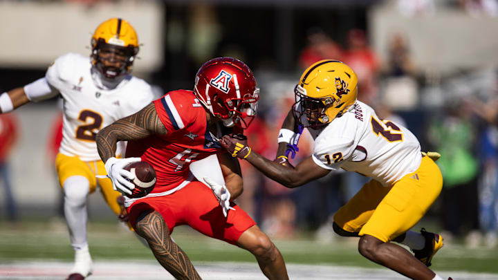 Nov 30, 2024; Tucson, Arizona, USA; Arizona Wildcats wide receiver Tetairoa McMillan (4) is tackled by Arizona State Sun Devils defensive back Javan Robinson (12) in the first half during the Territorial Cup at Arizona Stadium. Mandatory Credit: Mark J. Rebilas-Imagn Images