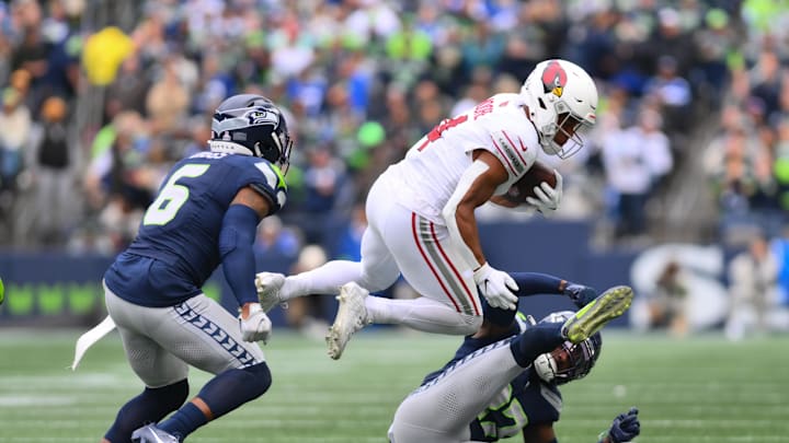 Oct 22, 2023; Seattle, Washington, USA; Arizona Cardinals wide receiver Rondale Moore (4) jumps over Seattle Seahawks cornerback Tre Brown (22) while carrying the ball during the first half at Lumen Field. Mandatory Credit: Steven Bisig-Imagn Images