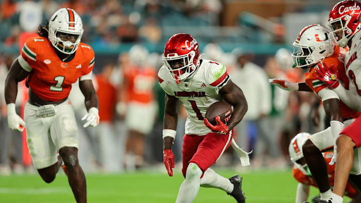 Oct 17, 2025; Miami Gardens, Florida, USA; Louisville Cardinals running back Isaac Brown (1) carries the football against Miami Hurricanes linebacker Mohamed Toure (1) and linebacker Wesley Bissainthe (31) during the first quarter at Hard Rock Stadium. Mandatory Credit: Sam Navarro-Imagn Images Oct 17, 2025; Miami Gardens, Florida, USA; Louisville Cardinals running back Isaac Brown (1) carries the football against Miami Hurricanes linebacker Mohamed Toure (1) and linebacker Wesley Bissainthe (31) during the first quarter at Hard Rock Stadium. Mandatory Credit: Sam Navarro-Imagn Images