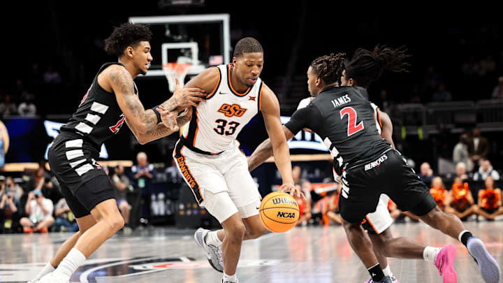 Mar 11, 2025; Kansas City, MO, USA; Oklahoma State Cowboys forward Abou Ousmane (33) drives to the basket around Cincinnati Bearcats guard Jizzle James (2) during the first half at T-Mobile Center. Mandatory Credit: William Purnell-Imagn Images
