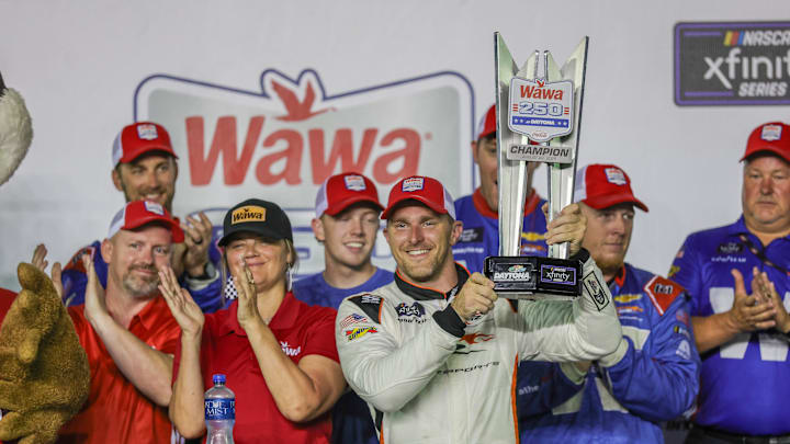 Aug 22, 2025; Daytona Beach, Florida, USA; NASCAR Xfinity Series driver Parker Kligerman (88) holds the trophy in Victory Lane after winning the Wawa 250 at Daytona International Speedway.