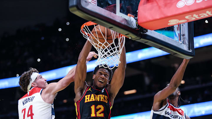 Nov 15, 2024; Atlanta, Georgia, USA; Atlanta Hawks forward De'Andre Hunter (12) dunks the ball against Washington Wizards forward Corey Kispert (24) and forward Alexandre Sarr (20) during the fourth quarter at State Farm Arena. Mandatory Credit: Jordan Godfree-Imagn Images