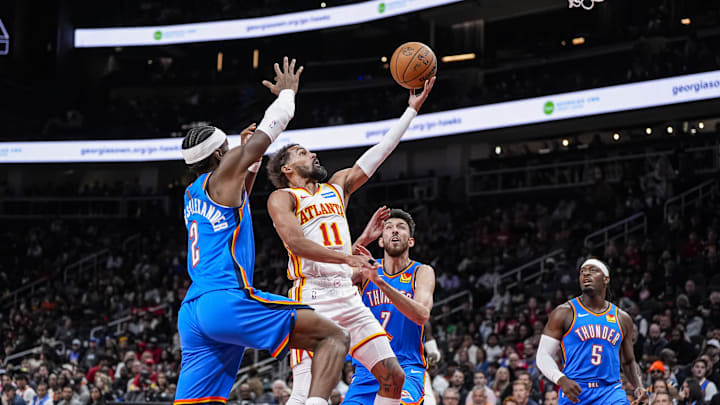 Oct 25, 2025; Atlanta, Georgia, USA; Atlanta Hawks guard Trae Young (11) goes to the basket between Oklahoma City Thunder guard Shai Gilgeous-Alexander (2) and center Chet Holmgren (7) during the first half at State Farm Arena. Mandatory Credit: Dale Zanine-Imagn Images Oct 25, 2025; Atlanta, Georgia, USA; Atlanta Hawks guard Trae Young (11) goes to the basket between Oklahoma City Thunder guard Shai Gilgeous-Alexander (2) and center Chet Holmgren (7) during the first half at State Farm Arena. Mandatory Credit: Dale Zanine-Imagn Images
