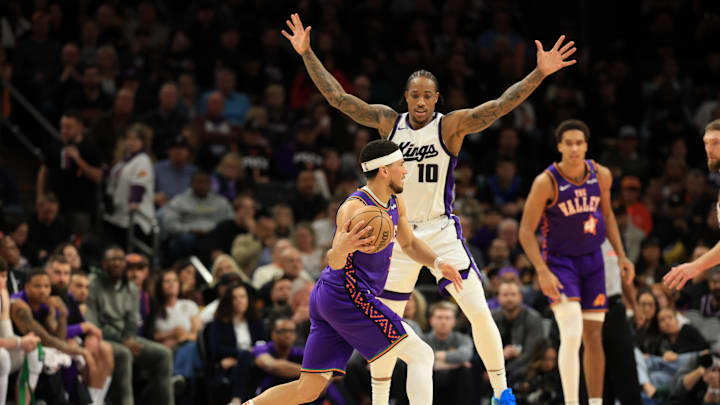 Mar 14, 2025; Phoenix, Arizona, USA; Phoenix Suns guard Devin Booker (1) dribbles the ball against Sacramento Kings forward DeMar DeRozan (10) during the second half at Footprint Center. Mandatory Credit: Mark J. Rebilas-Imagn Images