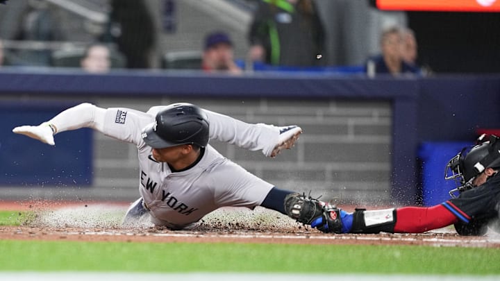 New York Yankees right fielder Juan Soto (22) slides into home plate scoring a run ahead of the tag from Toronto Blue Jays catcher Danny Jansen (9) during the fourth inning at Rogers Centre in 2024.