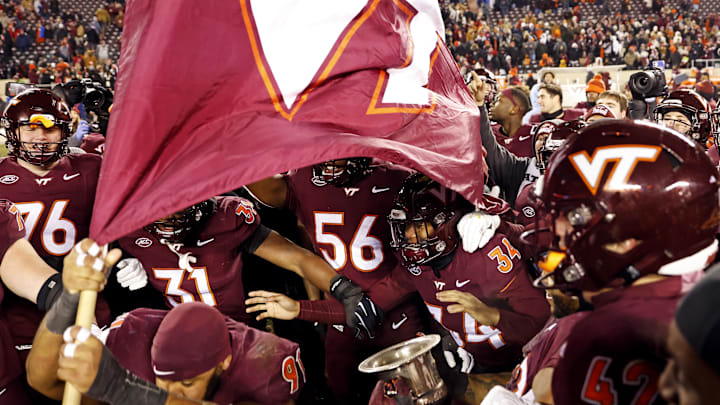 Nov 30, 2024; Blacksburg, Virginia, USA; The Virginia Tech Hokies celebrates with the Commonwealth Cup after beating Virginia Cavaliers at Lane Stadium. Mandatory Credit: Peter Casey-Imagn Images
