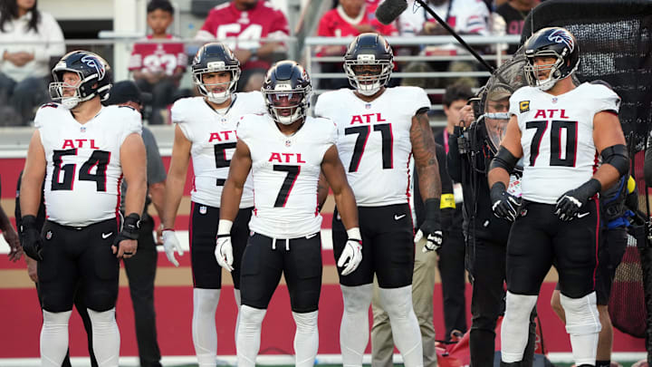 Atlanta Falcons running back Bijan Robinson stands alongside Ryan Neuzil and offensive tackles Elijah Wilkinson and Jake Matthews.