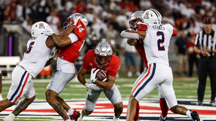 Aug 31, 2024; Tucson, Arizona, USA; New Mexico player runs through Arizona Wildcats linebacker Jacob Manu and Arizona Wildcats defensive back Treydan Stokes (2) during third quarter at Arizona Stadium. Mandatory Credit: Aryanna Frank-Imagn Images