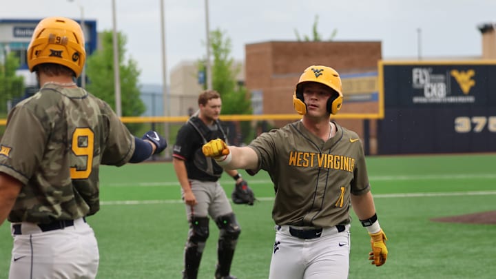 West Virginia utility infielder Sam White (11) is greeted by first baseman Grant Hussey (9) at the plate in the fourth inning against Texas Tech