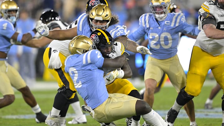 Nov 8, 2024; Pasadena, California, USA;   Iowa Hawkeyes running back Kaleb Johnson (2) is brought down by UCLA Bruins linebacker Oluwafemi Oladejo (2) for a loss of yardage in the first half at the Rose Bowl. Mandatory Credit: Jayne Kamin-Oncea-Imagn Images