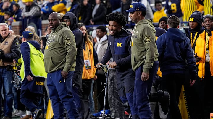 Injured Michigan running back Justice Haynes, center, talks to running backs coach Tony Alford, left, and Fred Jackson, senior offensive analyst/running backs, during warmups ahead of the Purdue game at Michigan Stadium in Ann Arbor on Saturday, November 1, 2025.