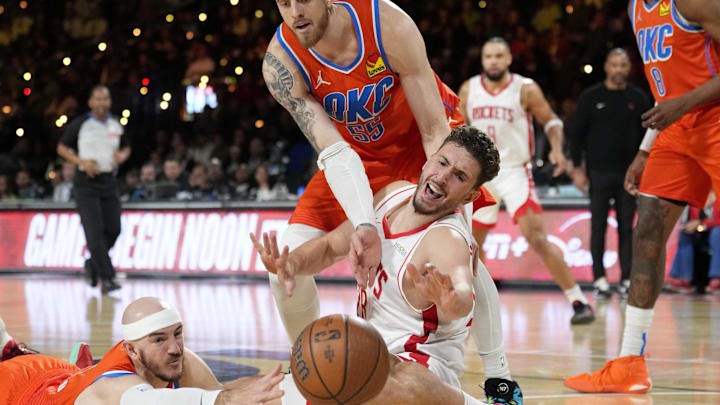 Dec 14, 2024; Las Vegas, Nevada, USA; Oklahoma City Thunder guard Alex Caruso (9) and center Isaiah Hartenstein (55) and Houston Rockets center Alperen Sengun (28) reach for a loose ball during the third quarter in a semifinal of the 2024 Emirates NBA Cup at T-Mobile Arena. Mandatory Credit: Kyle Terada-Imagn Images