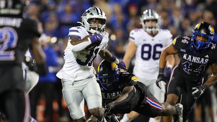 Nov 18, 2023; Lawrence, Kansas, USA; Kansas State Wildcats running back DJ Giddens (31) runs the ball against Kansas Jayhawks defensive lineman D.J. Withers (52) during the second half at David Booth Kansas Memorial Stadium. Mandatory Credit: Jay Biggerstaff-Imagn Images