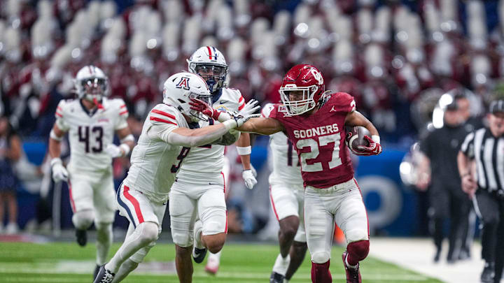 Dec 28, 2023; San Antonio, TX, USA;  Oklahoma Sooners running back Gavin Sawchuk (27) fends off Arizona Wildcats safety Gunner Maldonado (9) in the first half at Alamodome. Mandatory Credit: Daniel Dunn-Imagn Images