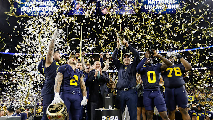 Michigan head coach Jim Harbaugh lifts up the trophy as players and coaches celebrate after 34-13 win over Washington to win the national championship game at NRG Stadium in Houston on Monday, Jan. 8, 2024.