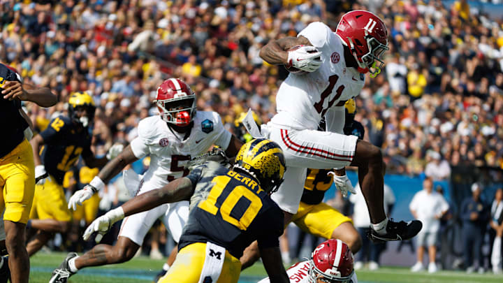 Dec 31, 2024; Tampa, FL, USA; Alabama Crimson Tide wide receiver Rico Scott (11) leaps over wide receiver Ryan Williams (2) and Michigan Wolverines defensive back Zeke Berry (10) during the first half at Raymond James Stadium. Mandatory Credit: Matt Pendleton-Imagn Images