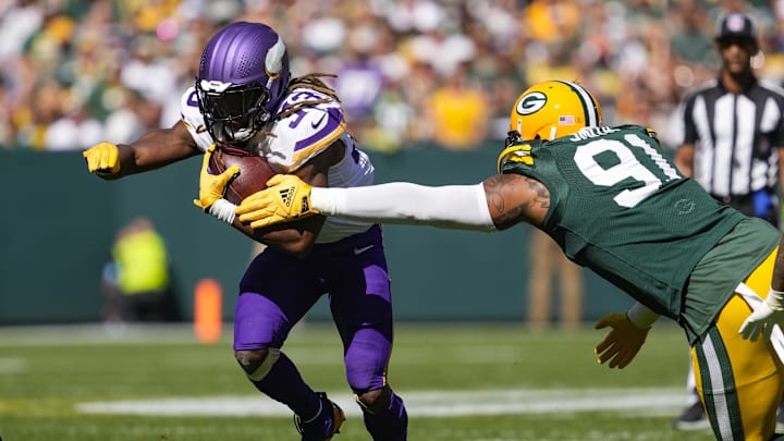 Sep 29, 2024; Green Bay, Wisconsin, USA;  Minnesota Vikings running back Aaron Jones (33) rushes with the football as Green Bay Packers defensive lineman Preston Smith (91) defends during the second quarter at Lambeau Field. Mandatory Credit: Jeff Hanisch-Imagn Images