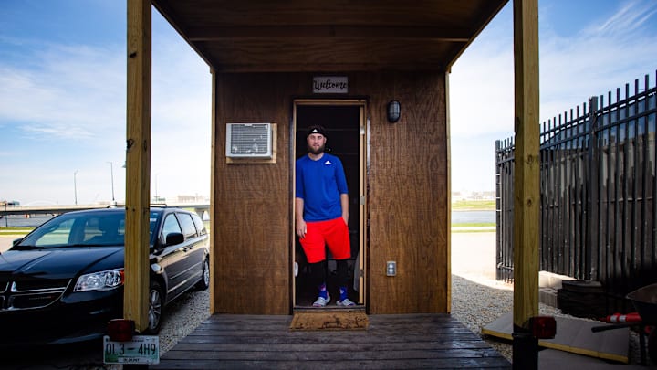 Iowa Cubs right handed pitcher Trevor Clifton stands for a photo in the tiny house he built to live