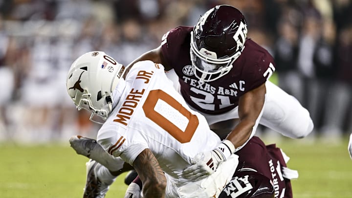 Nov 30, 2024; College Station, Texas, USA; Texas A&M Aggies defensive lineman Nic Scourton (11) and linebacker Taurean York (21) tackle Texas Longhorns wide receiver DeAndre Moore Jr. (0) during the first half. The Longhorns defeated the Aggies 17-7 at Kyle Field. Mandatory Credit: Maria Lysaker-Imagn Images  