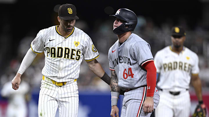 Aug 20, 2024; San Diego, California, USA; Minnesota Twins third baseman Jose Miranda (64) is tagged out by San Diego Padres shortstop Tyler Wade (14) after being caught in a rundown during the sixth inning at Petco Park. Mandatory Credit: Orlando Ramirez-Imagn Images