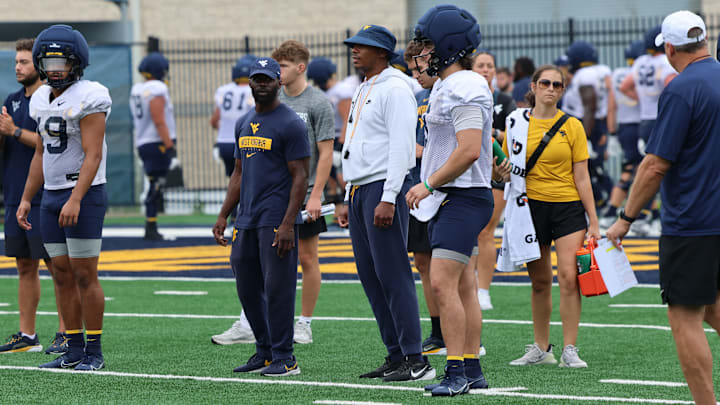 West Virginia University Offensive Analyst/Assistant Running Backs Coach Noel Devine (left) Assistant Quarterbacks Coach/Assistant to the Head Coach Pat White (middle), quarterback Nicco Marchiol (right)