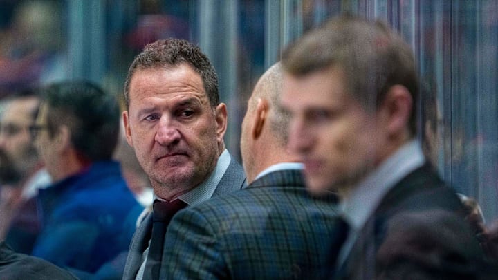 Adam Foote (left, facing camera) talks on the Canucks' bench in January.