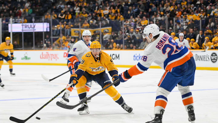 Apr 8, 2025; Nashville, Tennessee, USA;  Nashville Predators left wing Michael Bunting (58) blocks the pass of New York Islanders defenseman Alexander Romanov (28) during the third period at Bridgestone Arena. Mandatory Credit: Steve Roberts-Imagn Images