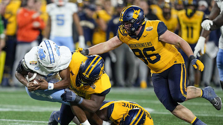 Dec 27, 2023; Charlotte, NC, USA; North Carolina Tar Heels quarterback Conner Harrell (15) is sacked by West Virginia Mountaineers defensive lineman Edward Vesterinen (96) during the second half at Bank of America Stadium. Mandatory Credit: Jim Dedmon-Imagn Images